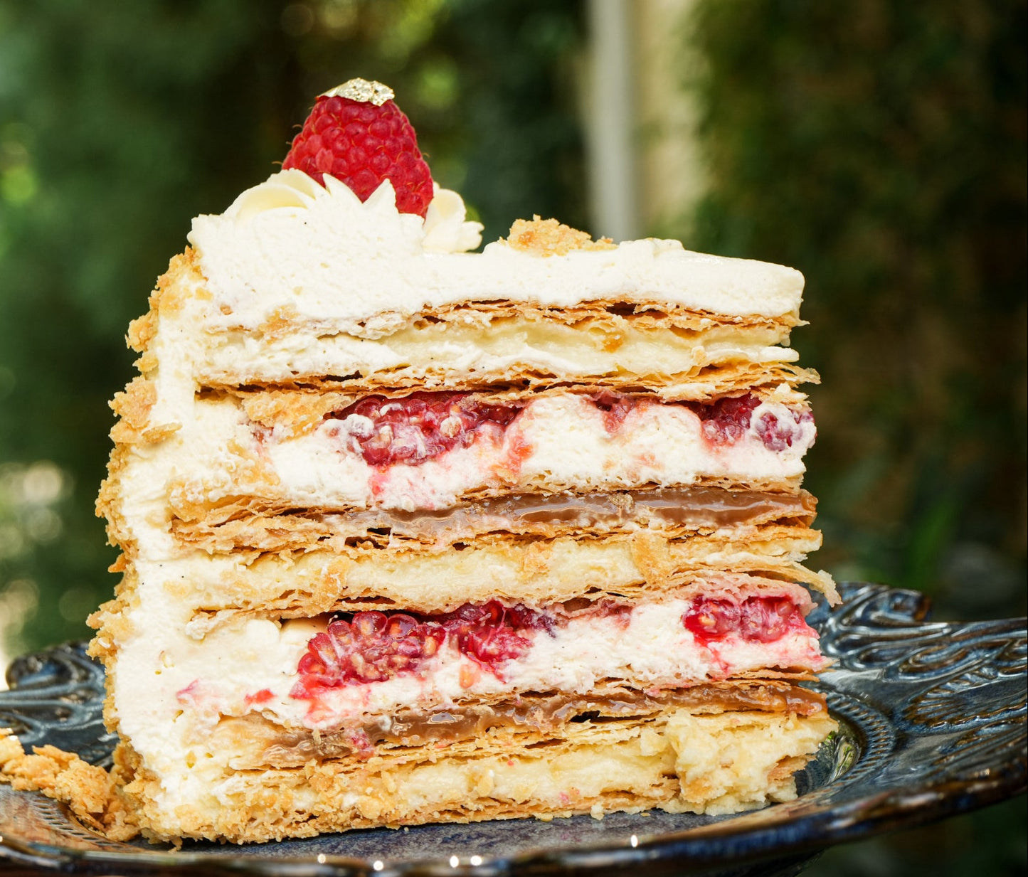 Chilean layered cake with puff pastry layers and pastry cream and raspberries.