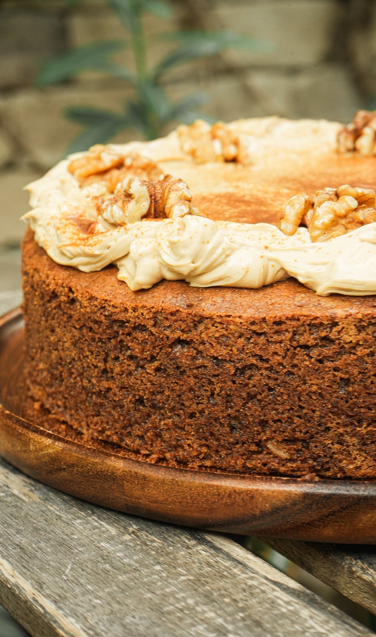 Coffee cake with white frosting and walnuts on a wooden board