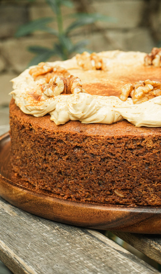 Coffee cake with white frosting and walnuts on a wooden board